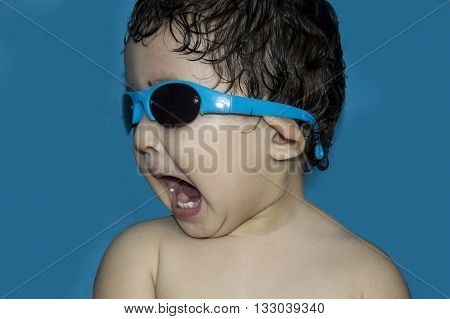 Portrait of a cute little toddler girl wearing sunglasses. Mouth wide open and looking away. Isolated.