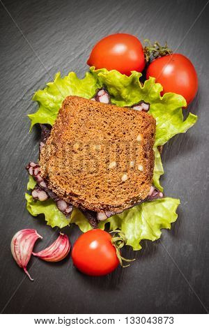 sandwich with sausage and vegetable on a dark background