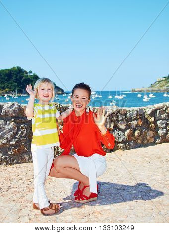 Happy Mother And Daughter Handwaving In Front Of Lagoon