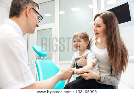 Smiling mother and her little son visiting dentist
