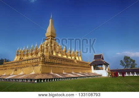 VIENTIANE LAOS - JANUARY 19 2012: Buddhist monk praying and walking around Wat Phra That Luang in Vientiane Lao PDR