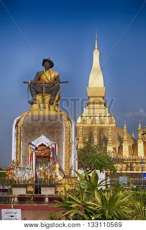 Statue of king Setthathirat sitting in front of the golden temple Wat That Luang Vientiane Laos
