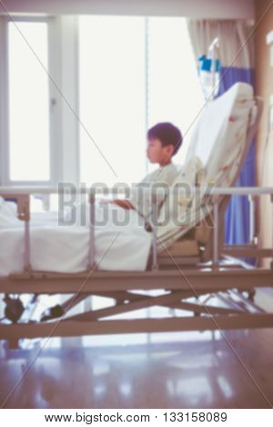 Abstract blurred background of illness asian child admitted at modern and comfortable equipped hospital room with infusion pump intravenous IV drip. Health care and people concept. Vintage style.
