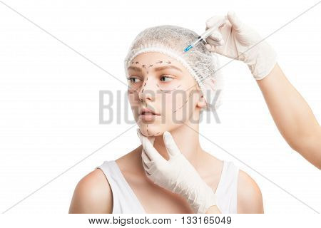 Portrait of young woman in medical hat being injected with syringe in face. Studio shot