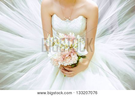 bridal bouquet in the hands on a magnificent white dress