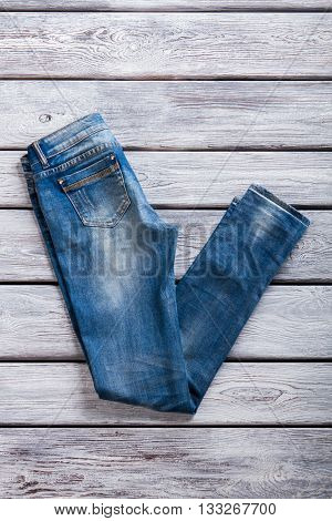 Simple jeans of blue color. Jeans on gray wooden background. Best merchandise in jeans store. Quality fabric and plain design.