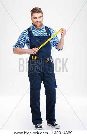 Smiling young worker standing and holding masuring tape