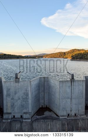 Weighted flood gates on Jindabyne Dam, confining the Snowy River.  The surrounding mountain landscape and cloudscape.  Lake Jindabyne is part of the ground breaking 'Snowy Mountains Hydro-Electric Scheme' diverting water from the Snowy River to the west o