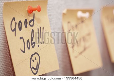 Adhesive note with Good Job text on a cork bulletin board