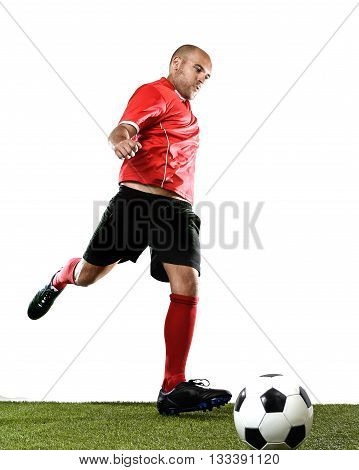 football player kicking ball in free kick shooting action isolated on white background wearing red jersey and socks and black shorts on green grass pitch