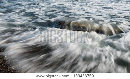 Sea waves flowing above a sea rock creating a beautiful nature water background. Long exposure photo.