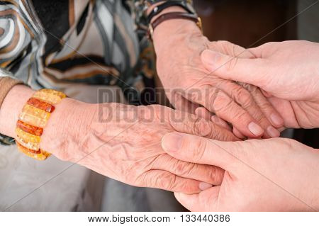 Senior Or Eldery Assistance Concept. Young Man Holds Hands Of Se