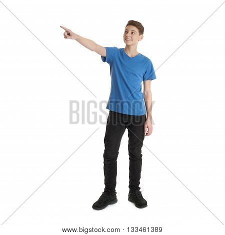 Cute teenager boy in blue T-shirt standing and poinitng up side over white isolated background full body