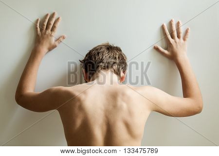 Rear View On Back Of Teen With Hands On Wall