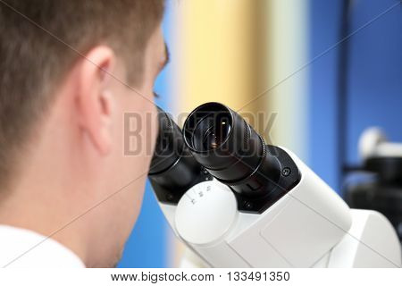 the man looking through a microscope closeup