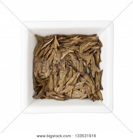 Longjing tea leaves in a square bowl isolated on white background