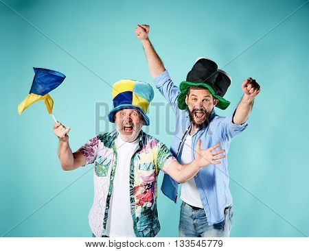 The two football fans with a flag of Ukraine over blue background