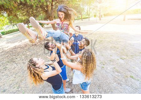 Group Of Friends Throwing A Woman In The Air