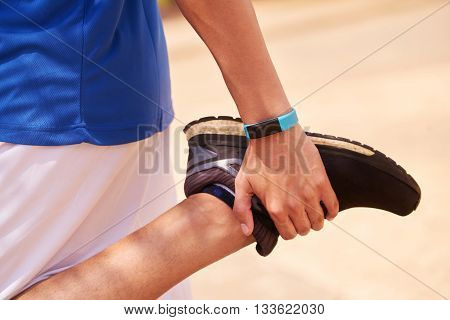Young people doing sport activities man runner jogging stretching leg using fit watch. Concept of leisure health recreation fitness lifestyle exercising workout
