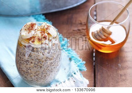 Overnight oats made with Chia seeds and fresh sliced bananas. Garnished with shaved chocolate and drizzeled honey and served outdoors. Extreme shallow depth of field.
