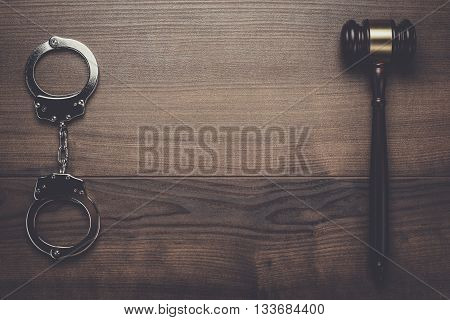 handcuffs and judge gavel on brown wooden background