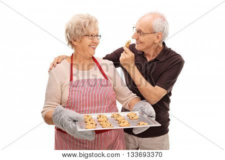 Elderly couple eating homemade chocolate chip cookies isolated on white background 