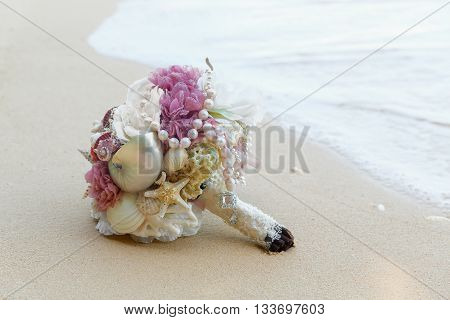 Wedding bridal bouquet made ​​of shells and pearls and other natural materials on the sand. Wedding and honeymoon in the tropics.