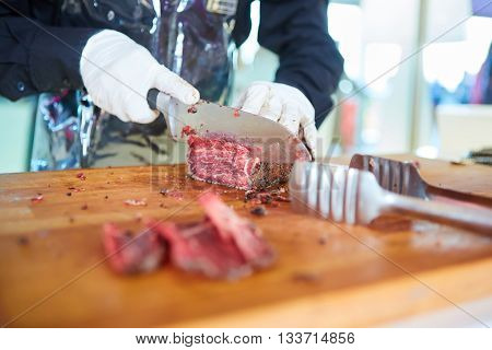 Butcher cutting slices of fresh beef. Shallow dof