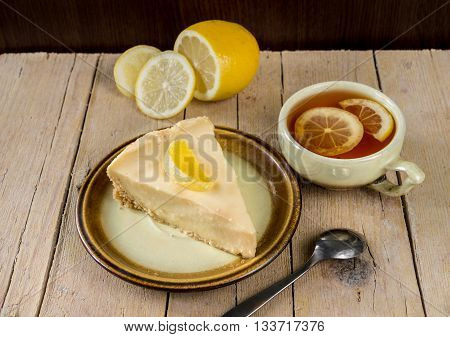 Lemon cheesecake with a cup of tea on a wooden background
