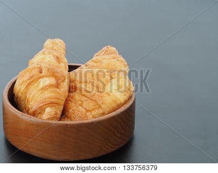 Fresh croissants bread in wood bowl on black table in background with area copy spcae for some text