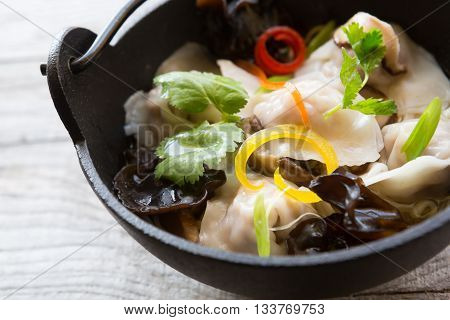 Bowl of traditional chenese soup with dumplings and mushrooms