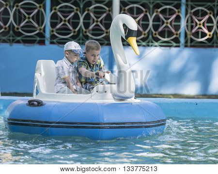 Rostov-on-Don Russia- May 29 2016: Two cheerful boy manage boat- swan in the park named after Ostrovsky