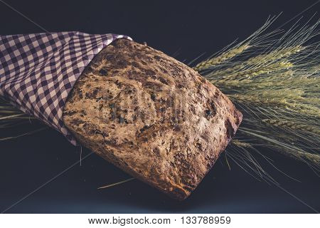 Vintage style: Homemade gluten-free and without yeast artisan bread with ears of barley wrapped in checkered napkin
