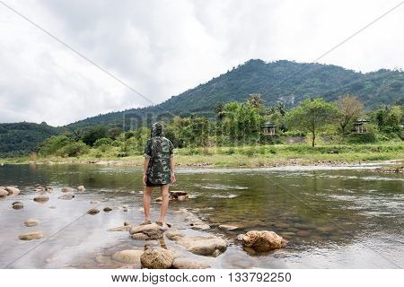 The back of a woman standing on the rocks in the brook
