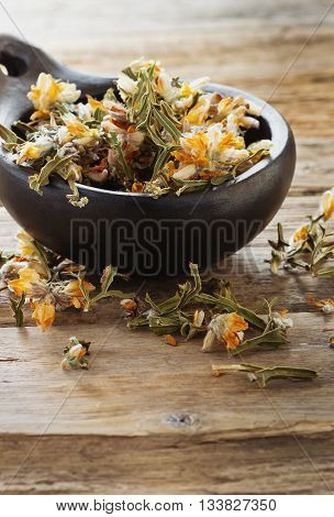 Dried medicinal herbs in a ceramic bowl on a wooden table.( Carqueja and Genista Tridentata). Close-up. Alternative treatment . Selective focus
