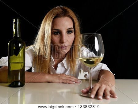 drunk blond woman alone in wasted depressed face expression looking thoughtful to white wine glass isolated on black background in alcohol abuse and alcoholic housewife concept