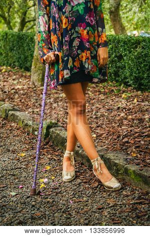 Young woman stands with walking stick on pebbled pathway