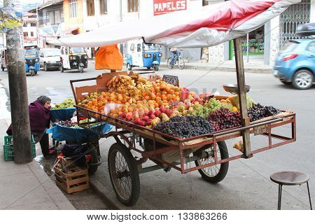 Cajamarca Peru - June 10 2016: Sleeping Andean woman sells fruit from bicycle street cart in Cajamarca Peru on June 10 2016