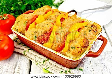 Cutlets of turkey meat baked with tomatoes and yellow pepper in a ceramic roasting pan on a kitchen towel, parsley on the background light wooden boards