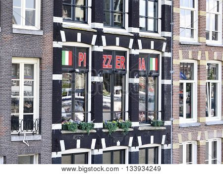 Pizzeria in an old house at a canal. Old houses of Amsterdam.