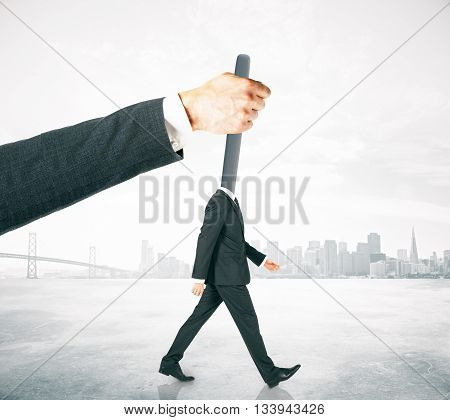 Hand manipulating lever-headed businessman on abstract foggy city background. Concept of control
