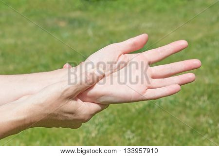 Female hands showing carpal tunnel syndrome problem outdoors