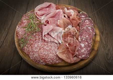 Wooden cutting board with various Italian salami