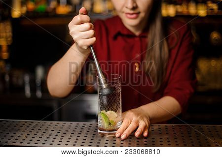 Female Bartender Pressing Down A Cane Sugar With Lime In A Glass At The Steel Bar Counter