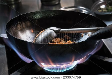 Chef Frying Rice With Meat On The Gas Stove With Fire At The Kitchen, Chef At Work, Pot With Fire. C