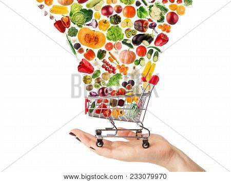 Female Hand Holding Grocery Cart With Vegetables And Fruits Falling In It Isolated On White. Healthy