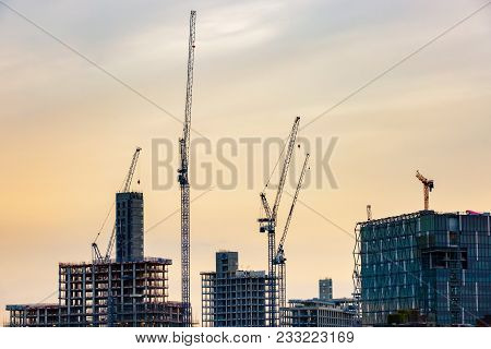 Silhouette Of New Skyscrapers Under Construction With Tall Cranes Against Colourful Sky. Constructio