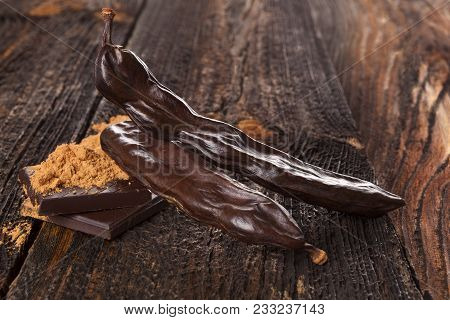 Carob Chocolate And Sweets, Carob Powder On Wooden Background.