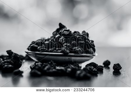 Black Raisin Or Kali Kishmish Or Zante Currant In A White Plate On Wooden Surface In Dark Gothic Col