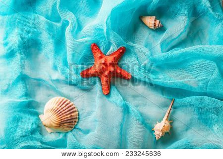 Several Seashells And Bright Red Starfish On Cian Cloth Background. Summer Holiday Concept